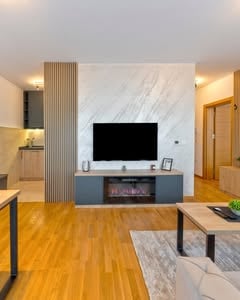 Dnevni boravak apartmana Boréa sa mermernim zidom, televizorom i elektro kaminom